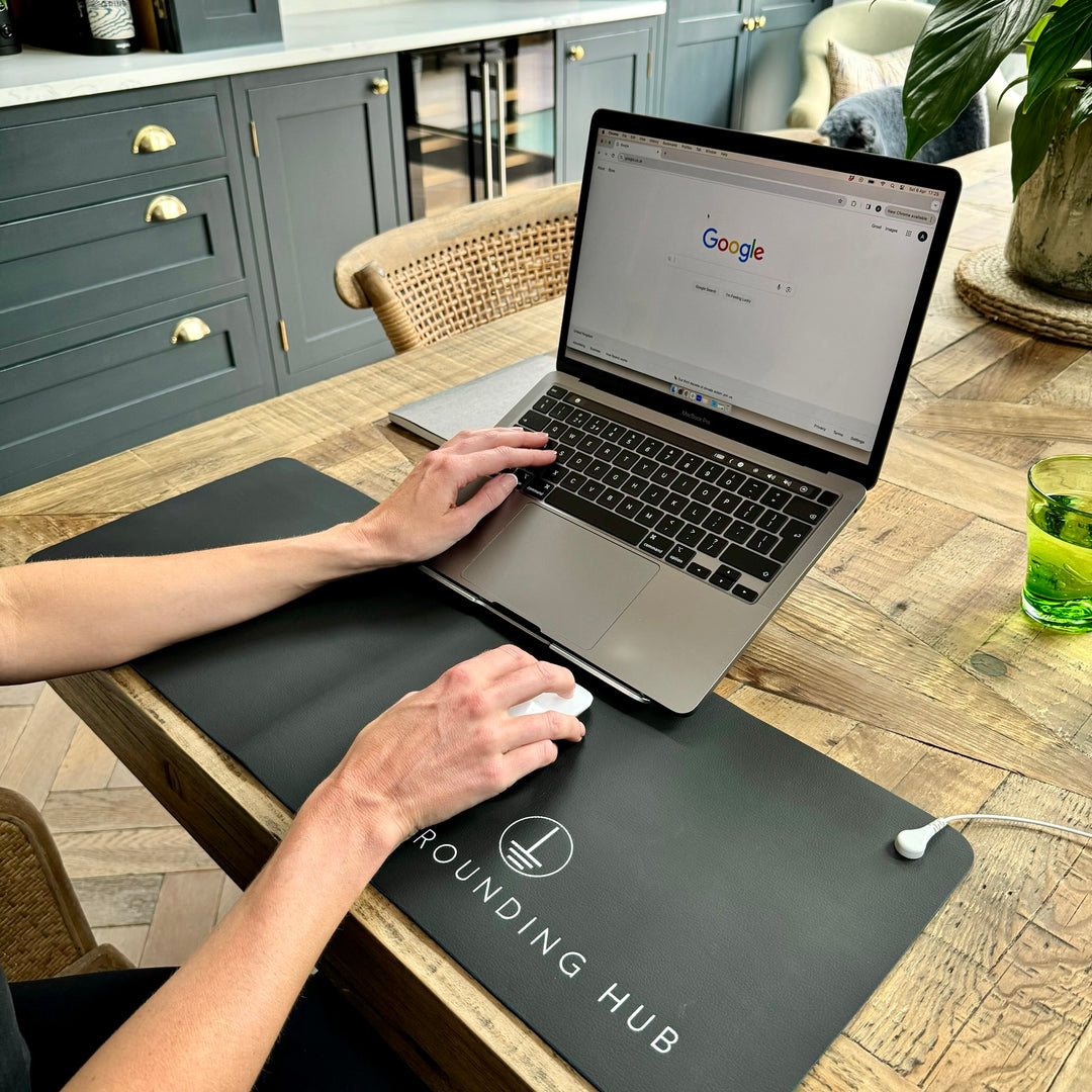 A lady working from home using her grounding desk mat working at her laptop